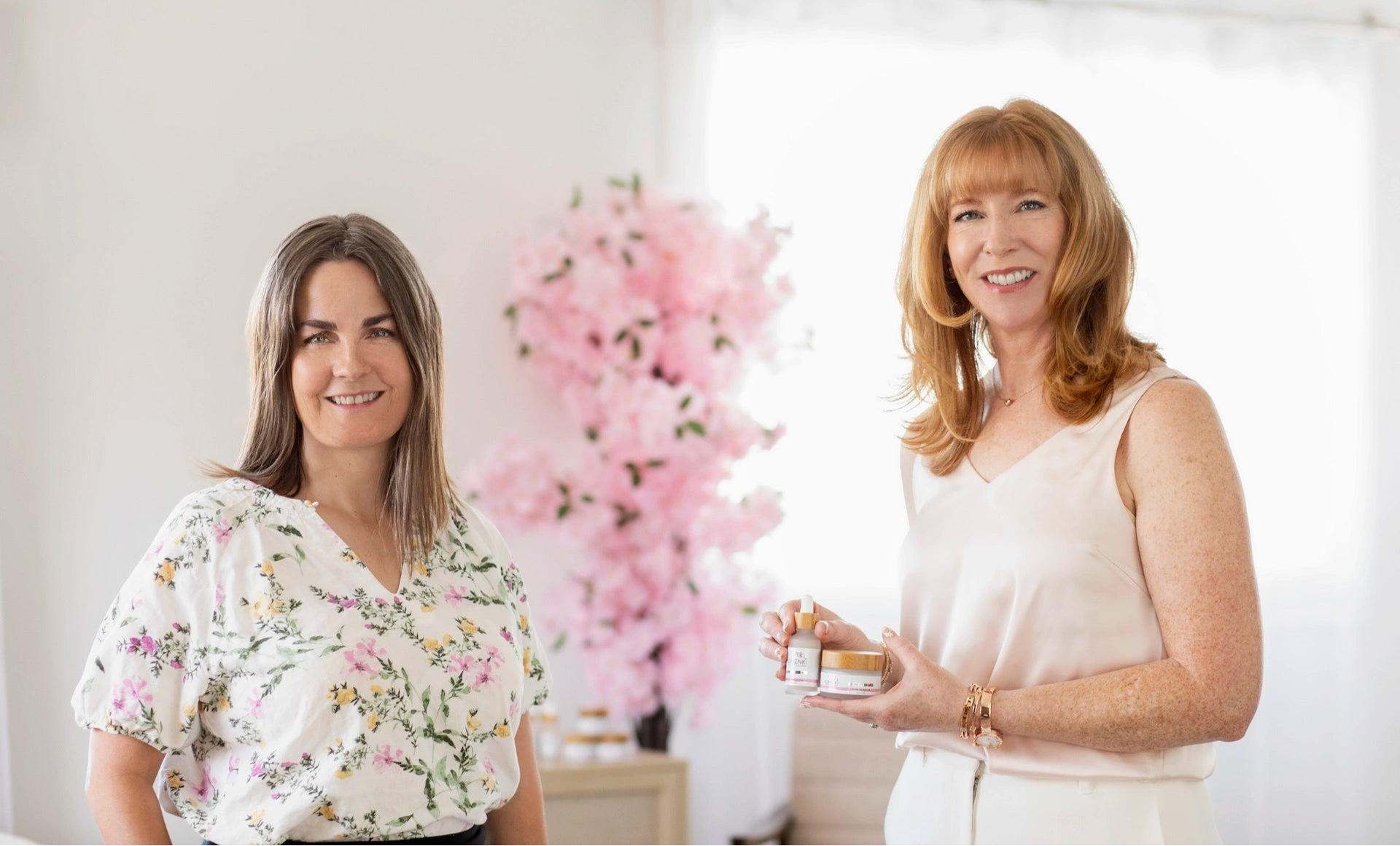 Konenki Skincare's brand founders, standing in a bright room with pink flowers in the background.
