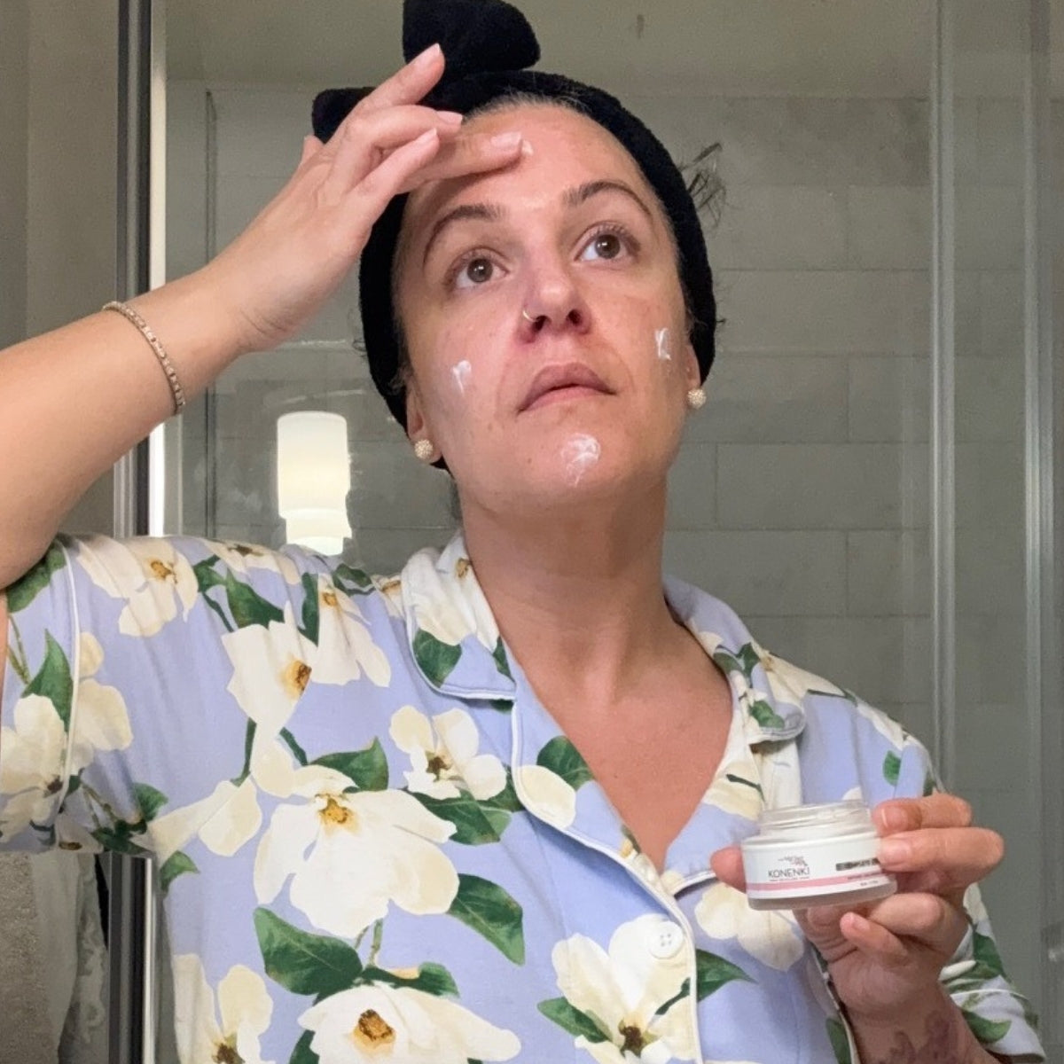 A woman demonstrates the Konenki Complete Serum on her skin.